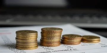 Pilas de monedas de euro sobre un contrato de depósito, simbolizando ahorro y rentabilidad.